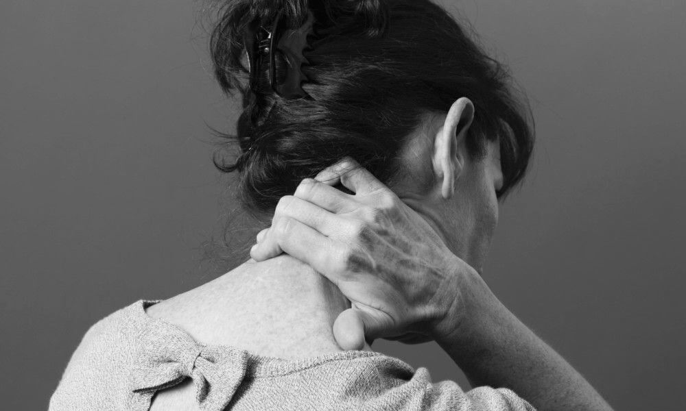 Egy nő a stressztől beállt nyakát masszírozza.