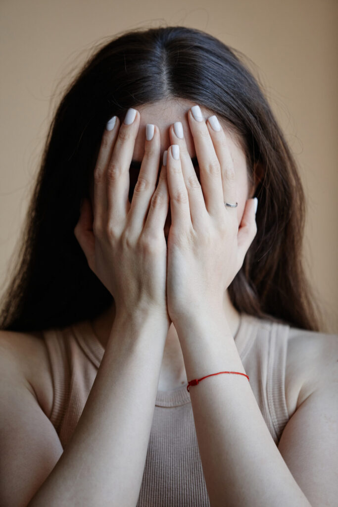 Szorongó nő a kezeibe temeti a fejét.